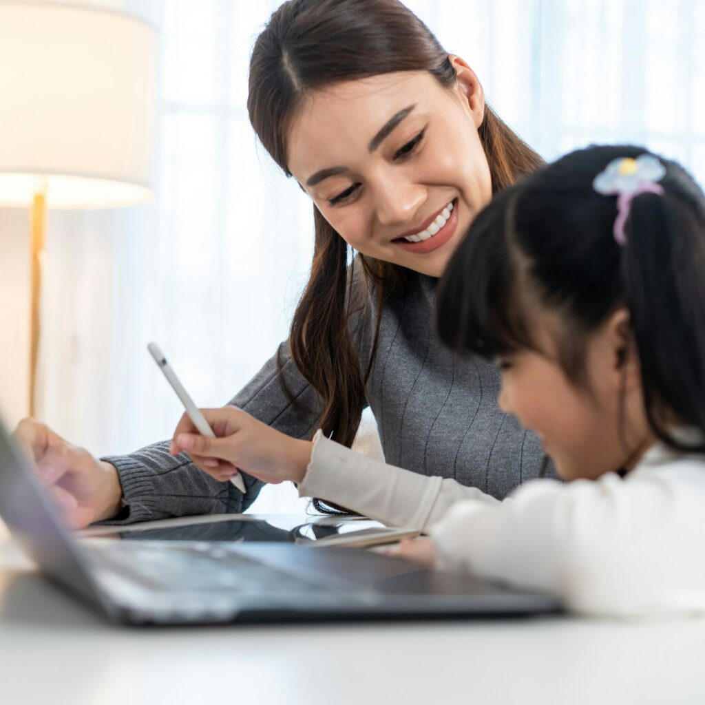 Asian little young girl kid learning online class at home with mother.